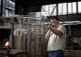 Ein Glasbläser bläst ein MarkThomas Glas