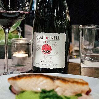 Rotwein auf einem Gedeckten Tisch hinter einem Teller mit Fisch