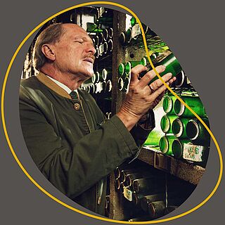 Ein Mann nimmt sich eine Flasche aus einem Weinlager