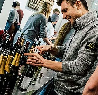 Elias Schlichting öffnet eine Flasche bei einem Team-Event