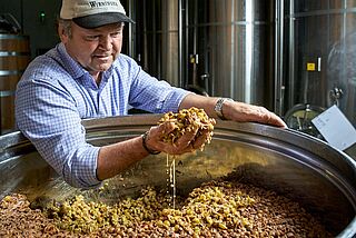 Winzer Fritz bei der Verarbeitung von Maische auf dem Weingut Wieninger
