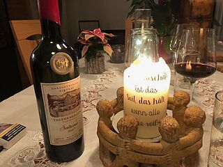 Weinflasche auf einem gedeckten Tisch neben einer Kerze