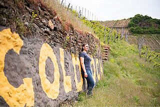 Winzerin Caroline Diek angelehnt an einer Mauer auf dem Weingut Schlossgut Diel Winzerin Caroline Diek angelehnt an einer Mauer auf dem Weingut Schlossgut Diel