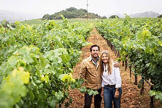 Winzerfamilie auf dem Weinfeld Favia, mit Weinbergen im Hintergrund