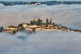 Dorf auf einem Berg, umgeben mit Wolken